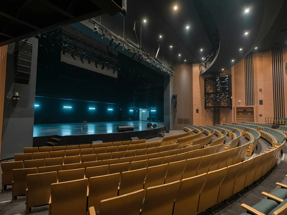 A wraparound theatre auditorium facing an empty lit stage